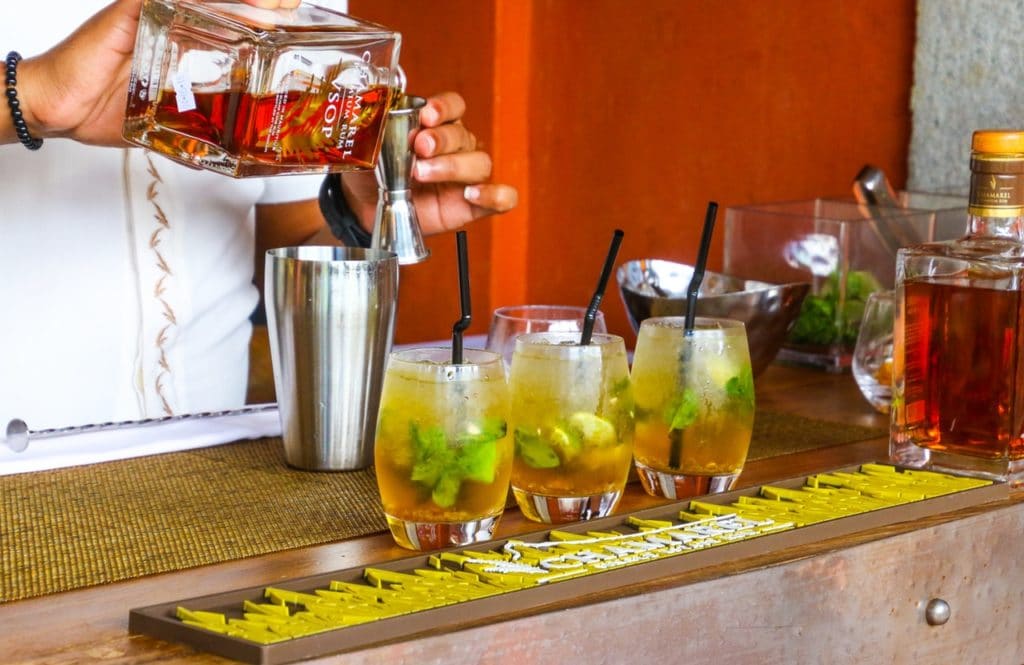 Barman servant des cocktail dans un bar en Australie avec 3 verres devant lui.